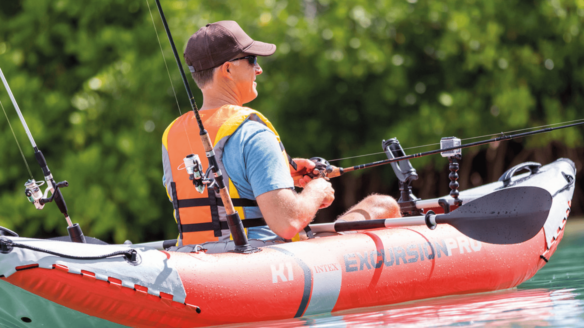 A man fishing from a red Intex Excursion Pro K1 inflatable kayak equipped with fishing rod holders and a camera mount.