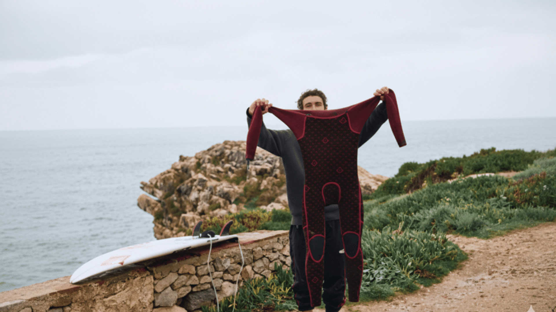 man holding his wetsuit to dry