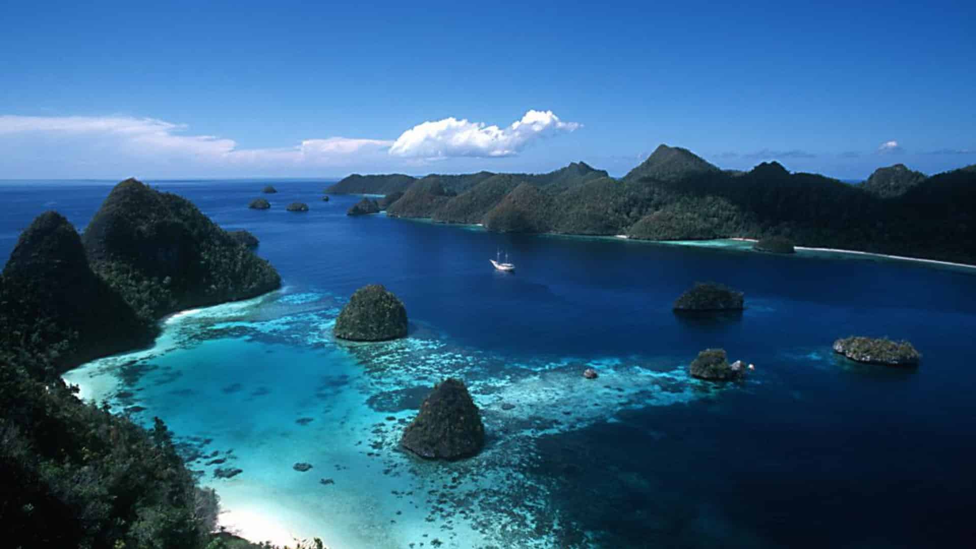 Aerial view of limestone islets and bright blue lagoon water under a clear sky.