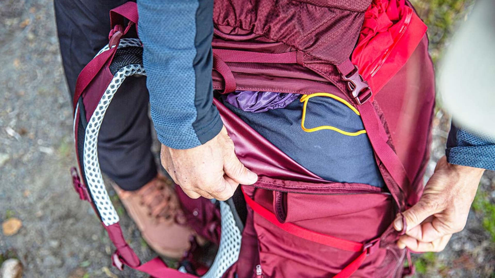 Close-up of Osprey Aura AG 65 backpack side zipper opening showing packed gear and internal storage access during use.