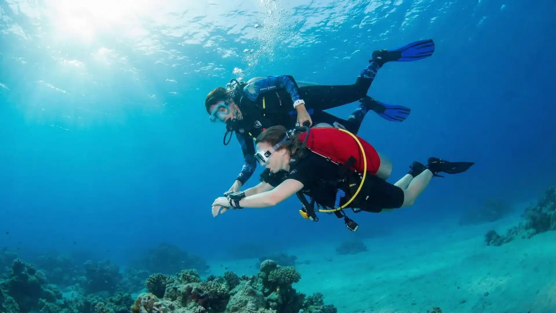 A skin diving instructor teaching scuba basics to a learned skin diver.