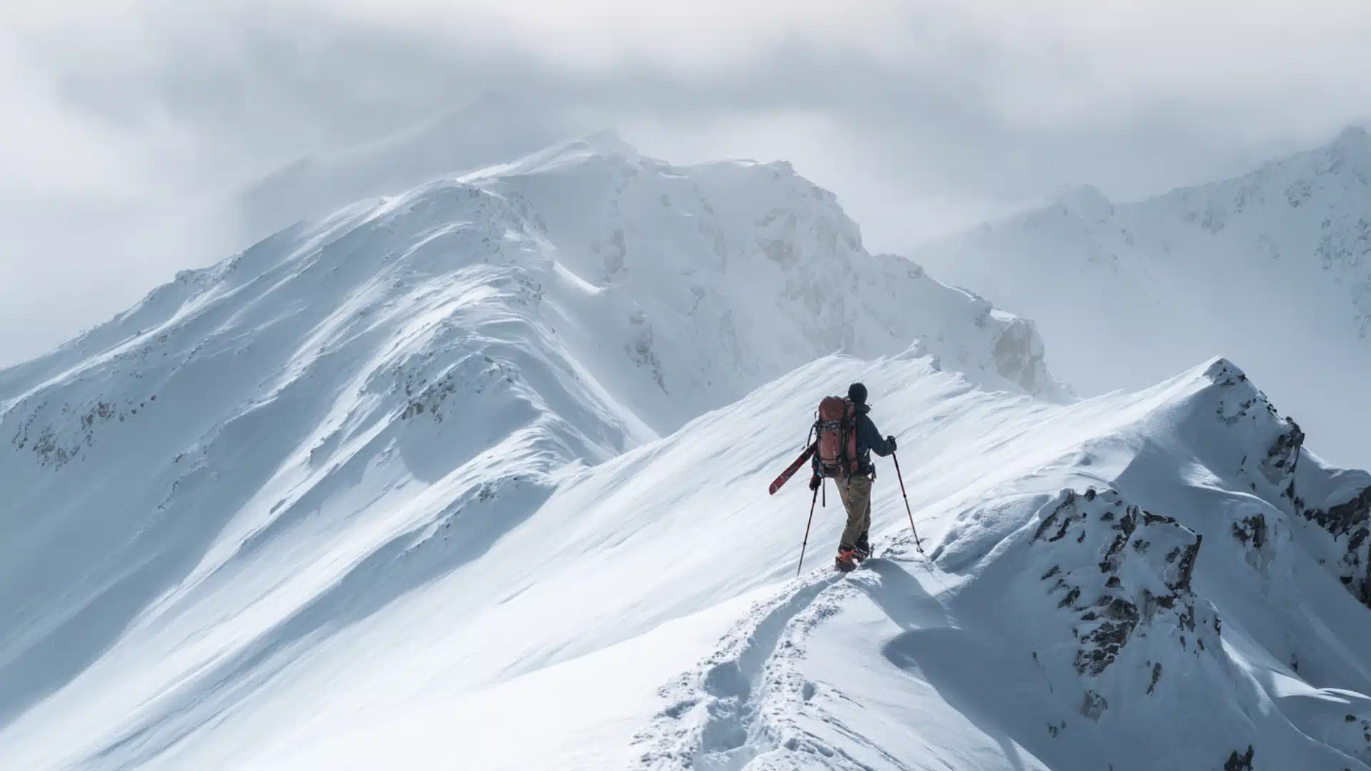 Backcountry skier climbing untouched snowy ridge in remote mountain wilderness..
