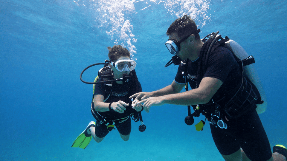 Beginner scuba diver training with instructor in ocean during certification
