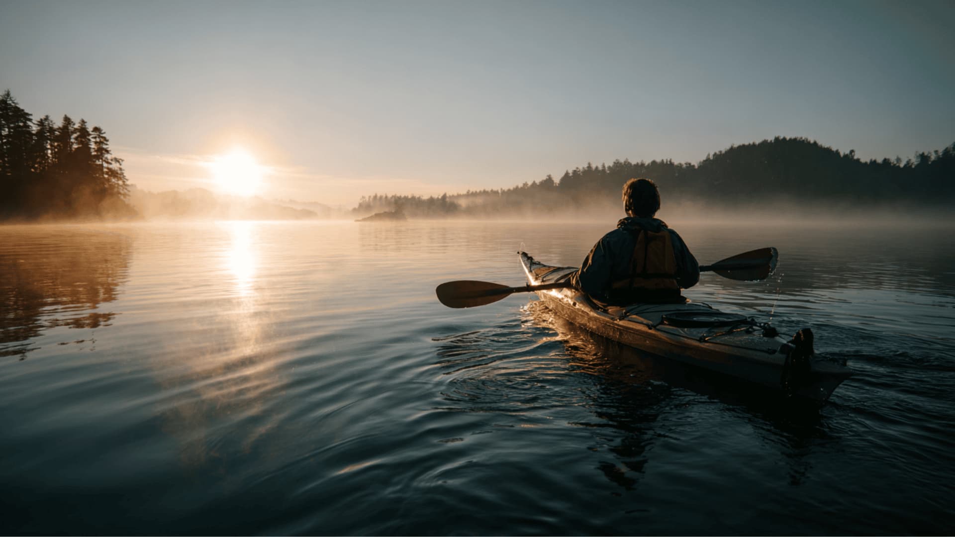Kayaker on calm lake in cool weather showing cold water risk