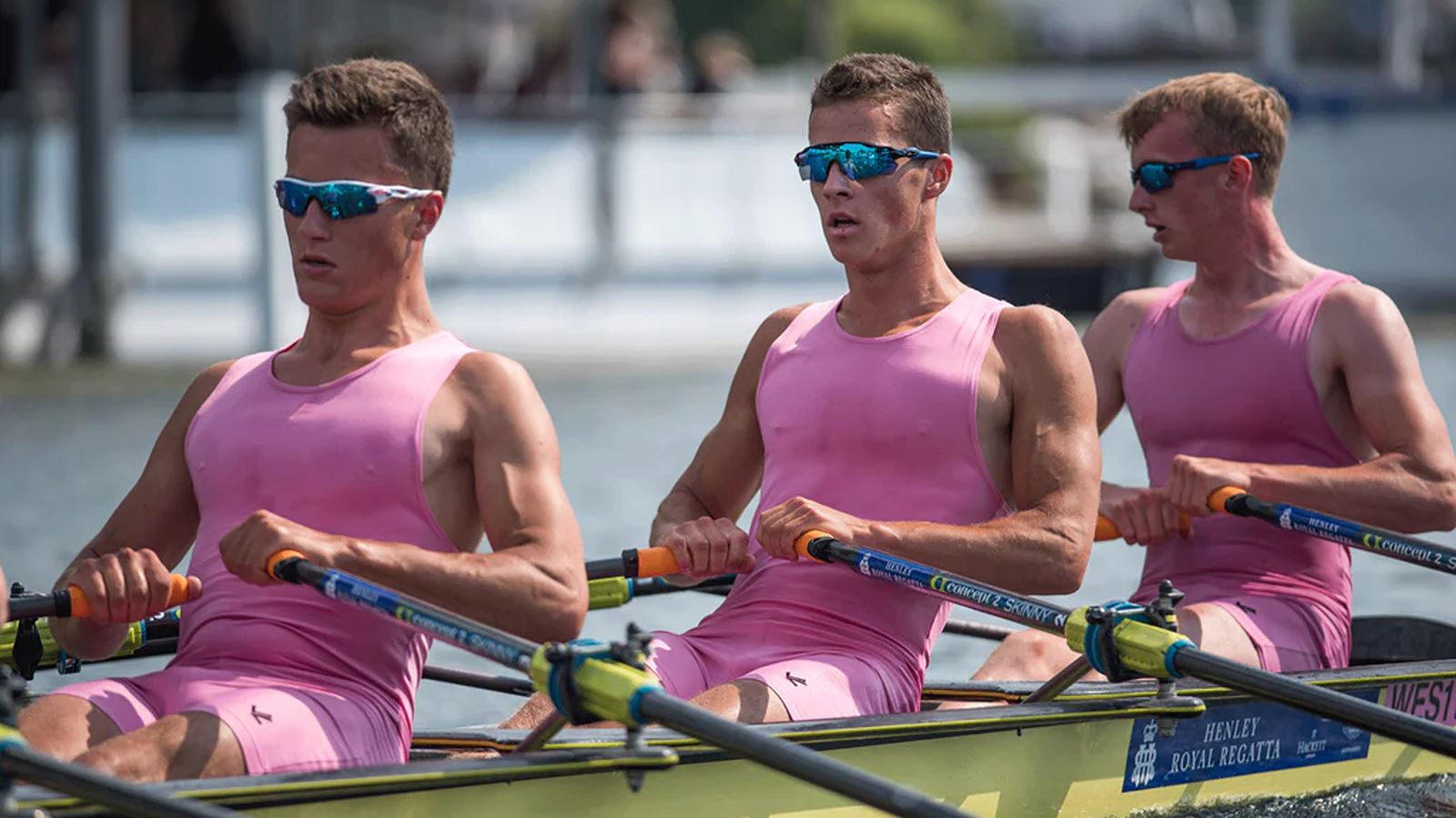 Male rowers in pink uniforms racing in a crew boat during a regatta