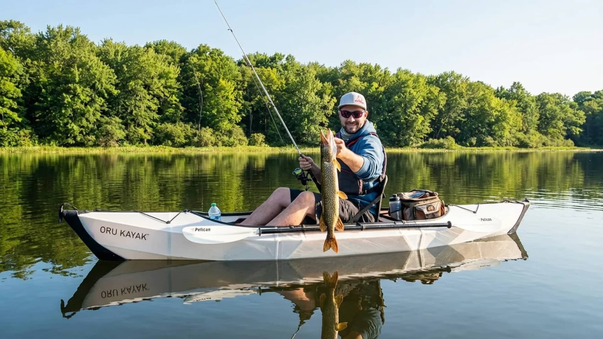 Smiling angler shows a fresh catch from a white kayak on a calm tree-lined lake