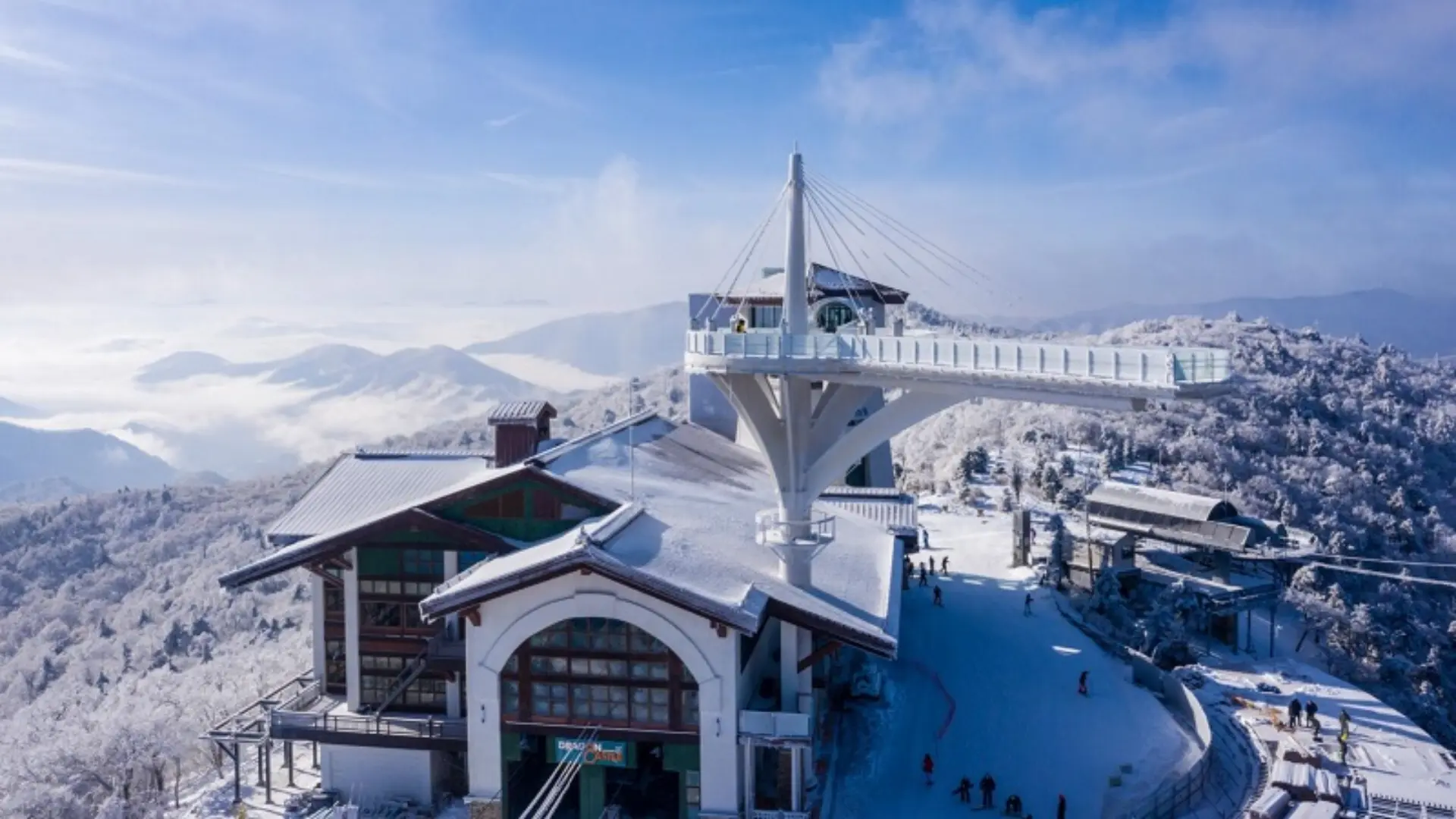 Snow-covered mountain viewpoint with observation deck, ski lift station, and scenic winter landscape above the clouds