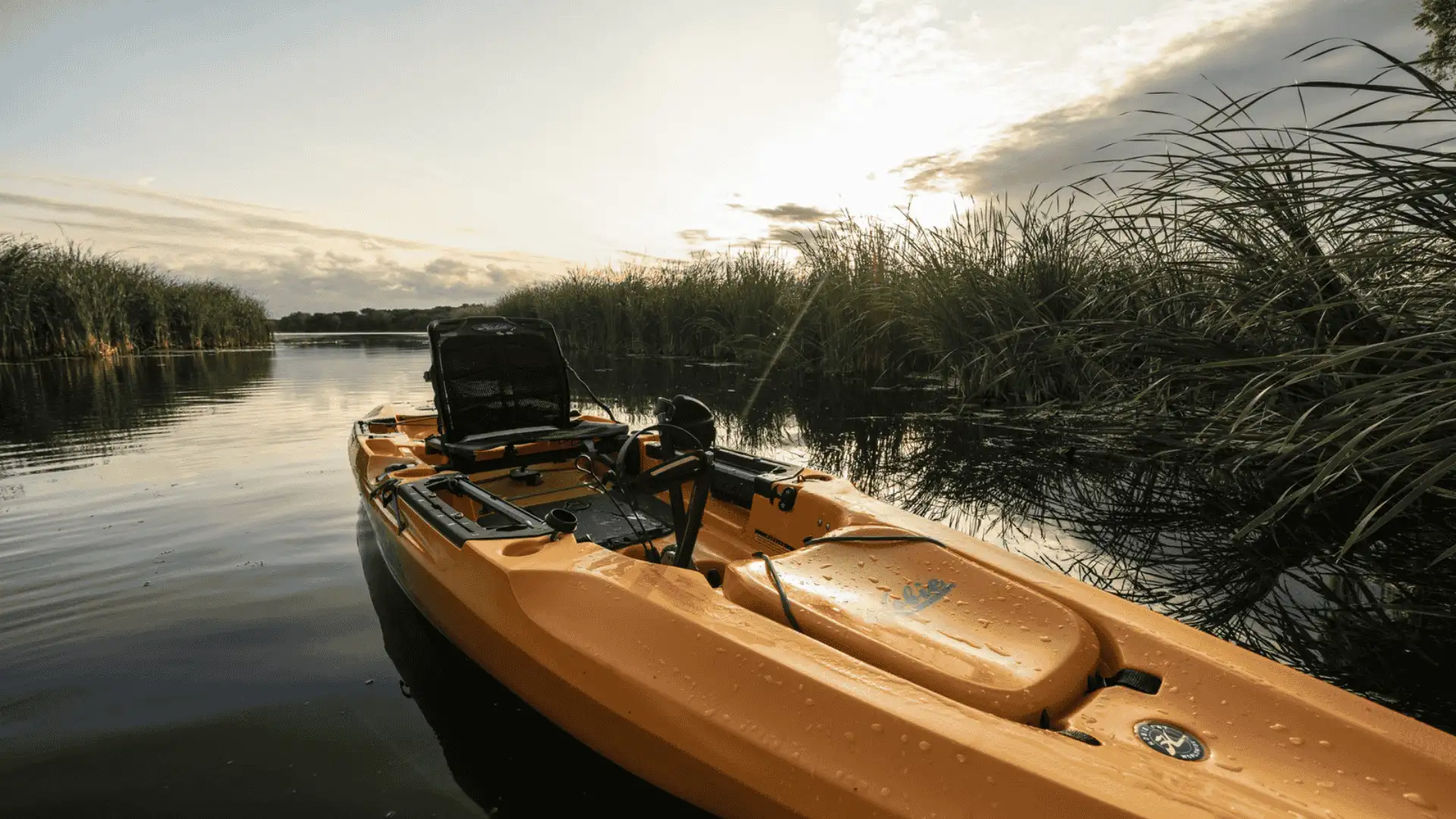 A Hobie Outback kayak on calm water, featuring a fishing rod positioned for angling