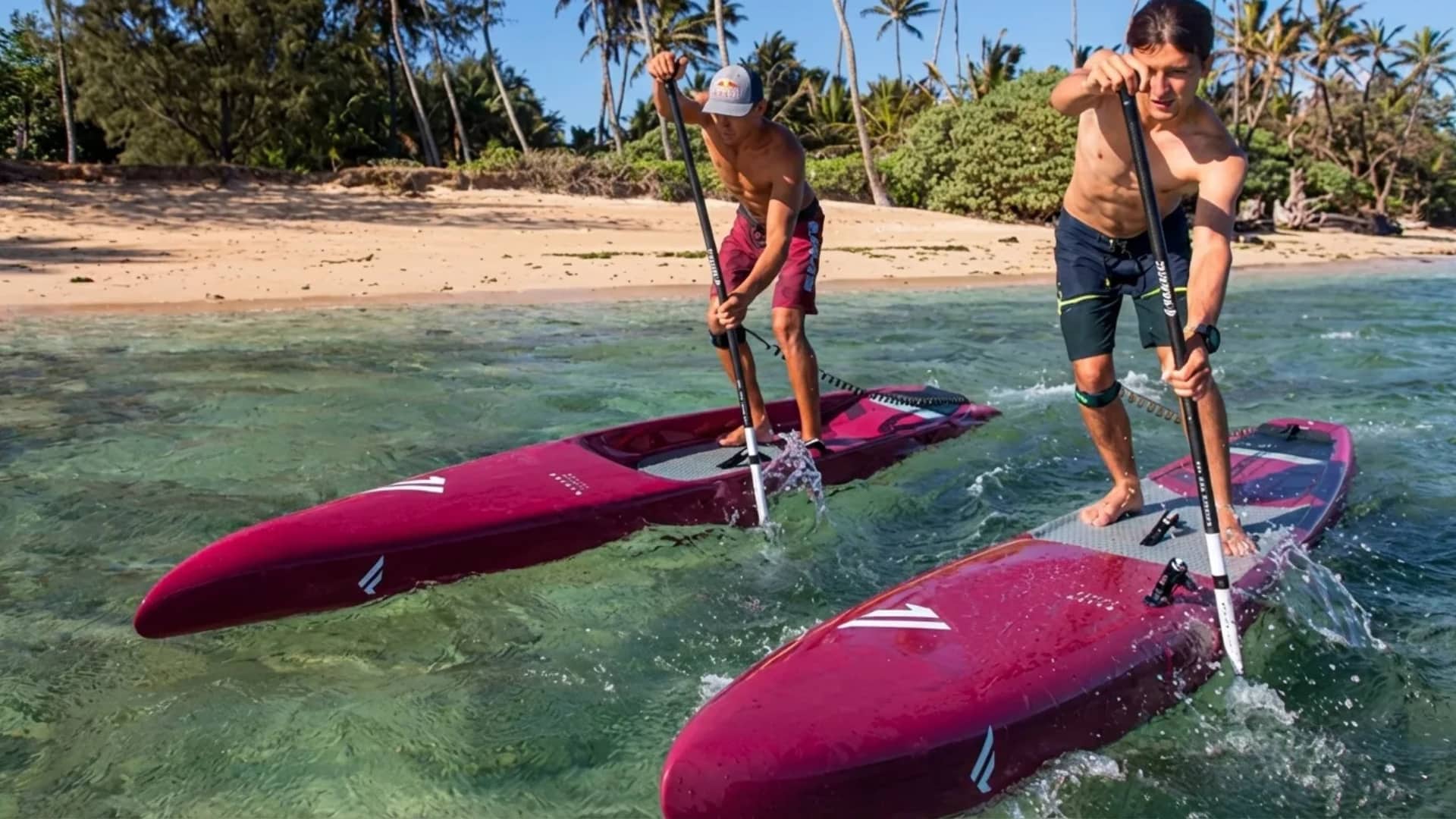 two-men-paddling-red-boards-in-shallow-tropical-water