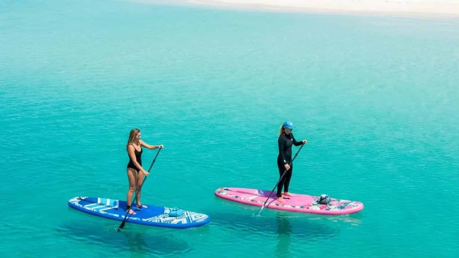 two-women-paddle-inflatable-boards-in-turquoise-water