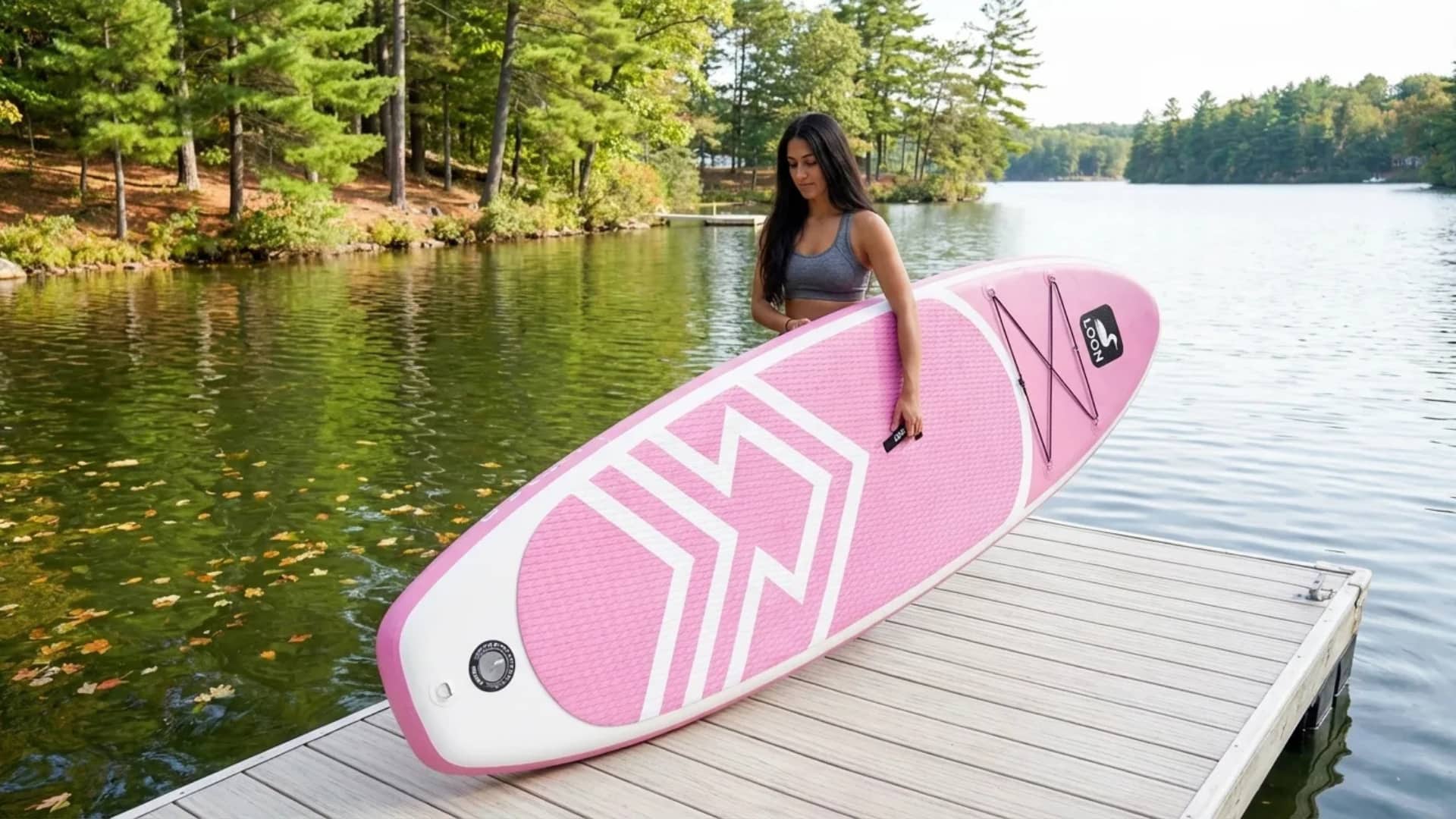 woman-carrying-pink-paddle-board-on-lake-dock
