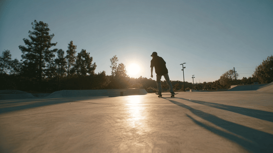 Beginner practicing skateboarding in an empty skate park with wide open space and smooth ground