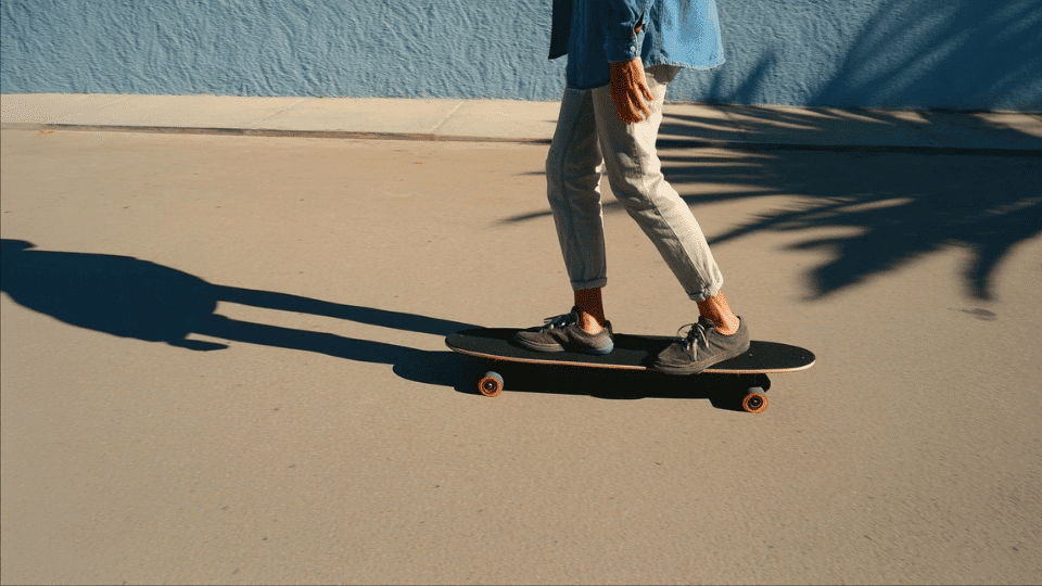 riding skateboard forward on smooth pavement while pushing with back foot