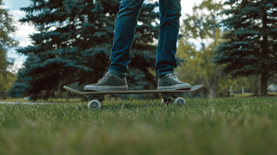 standing balanced on a skateboard on grass with relaxed posture and knees slightly bent