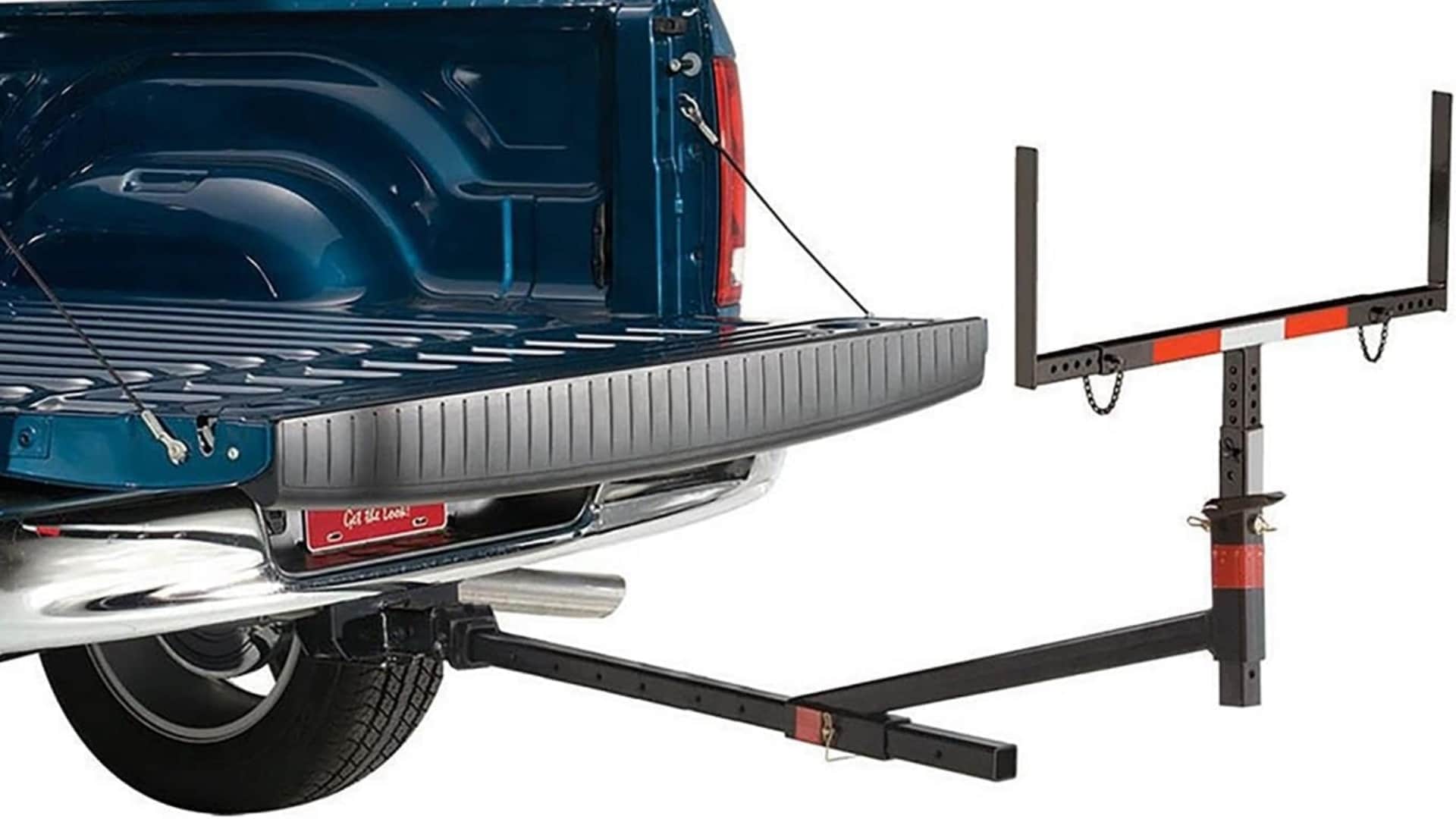 A black adjustable hitch-mounted bed extender installed behind the open tailgate of a blue pickup truck.