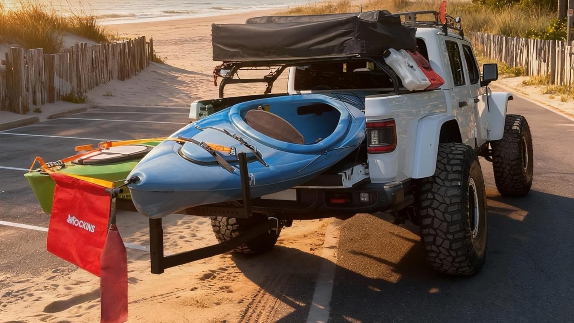 Two kayaks secured in a white Jeep truck bed using a Mockins 2-in-1 bed extender with a red safety flag.