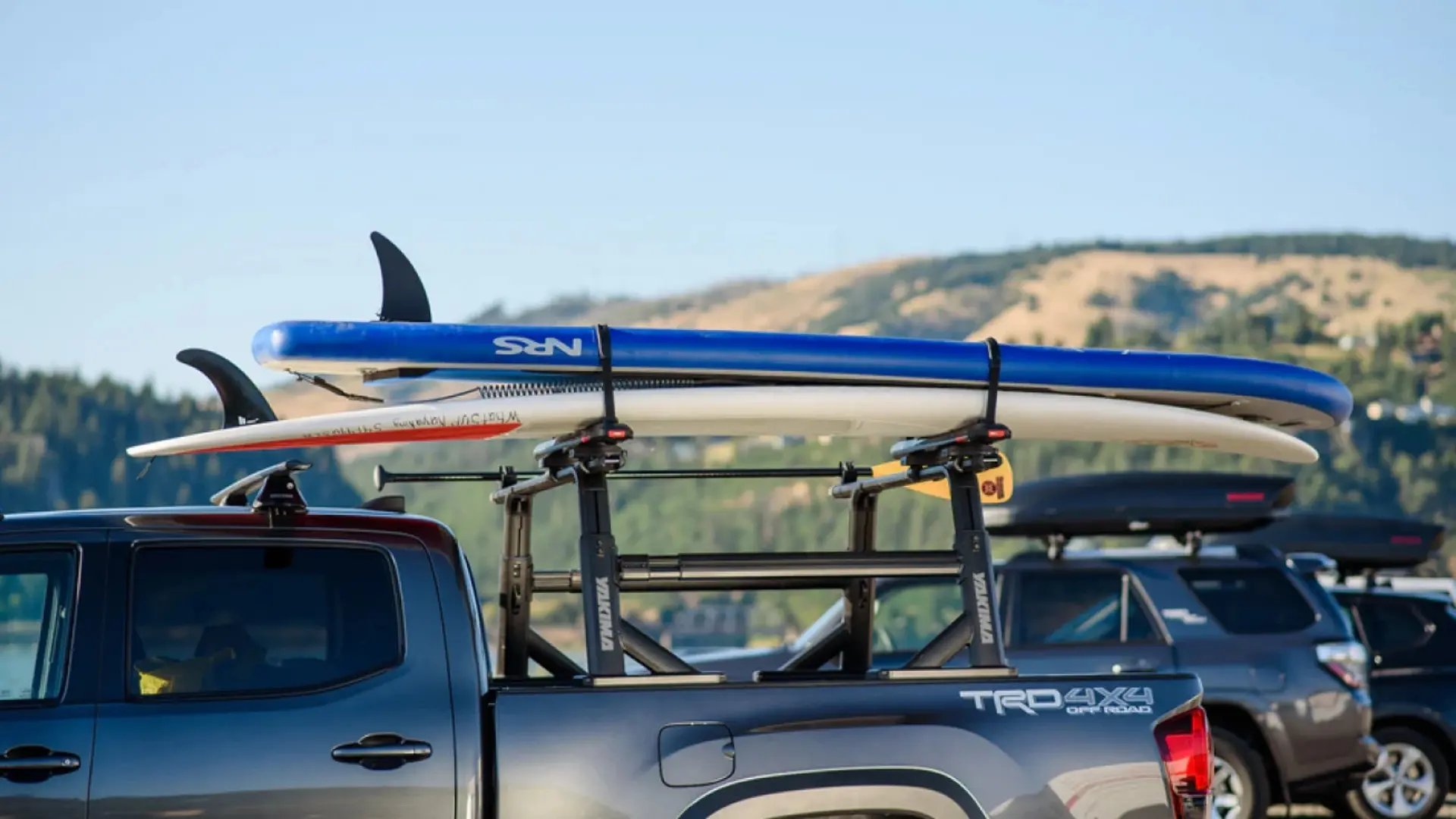 Two paddleboards secured to a Yakima OverHaul HD truck bed rack on a grey TRD 4x4 pickup truck.