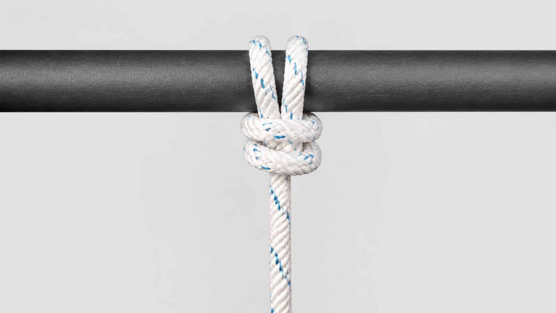 White and blue rope tied in a boom clove hitch knot around a black horizontal pole, close-up view