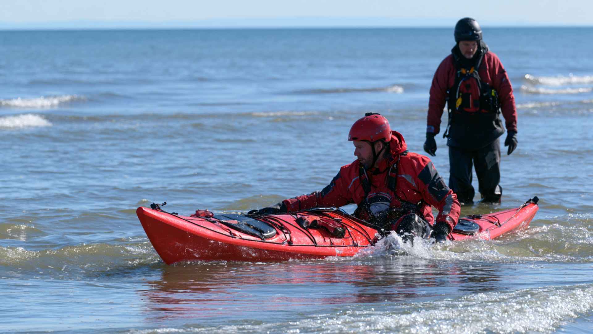Kayaker practicing self-rescue technique in calm coastal water with paddle float assistance
