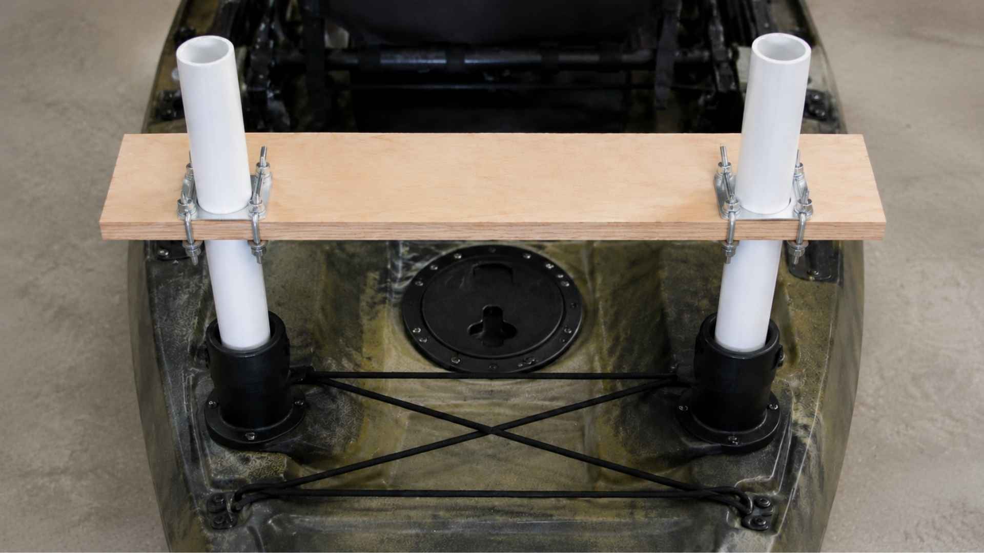 Board bolted to PVC pipes using clamps securing stable kayak mount frame