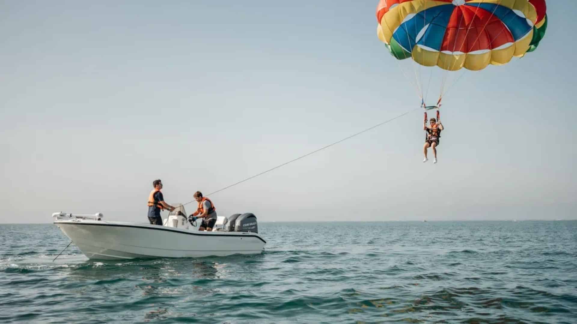 Parasail canopy lifting rider high above ocean as boat speed and towline create flight height