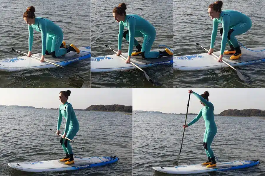 A person demonstrates step-by-step how to stand up on a paddle board from kneeling position on calm water.