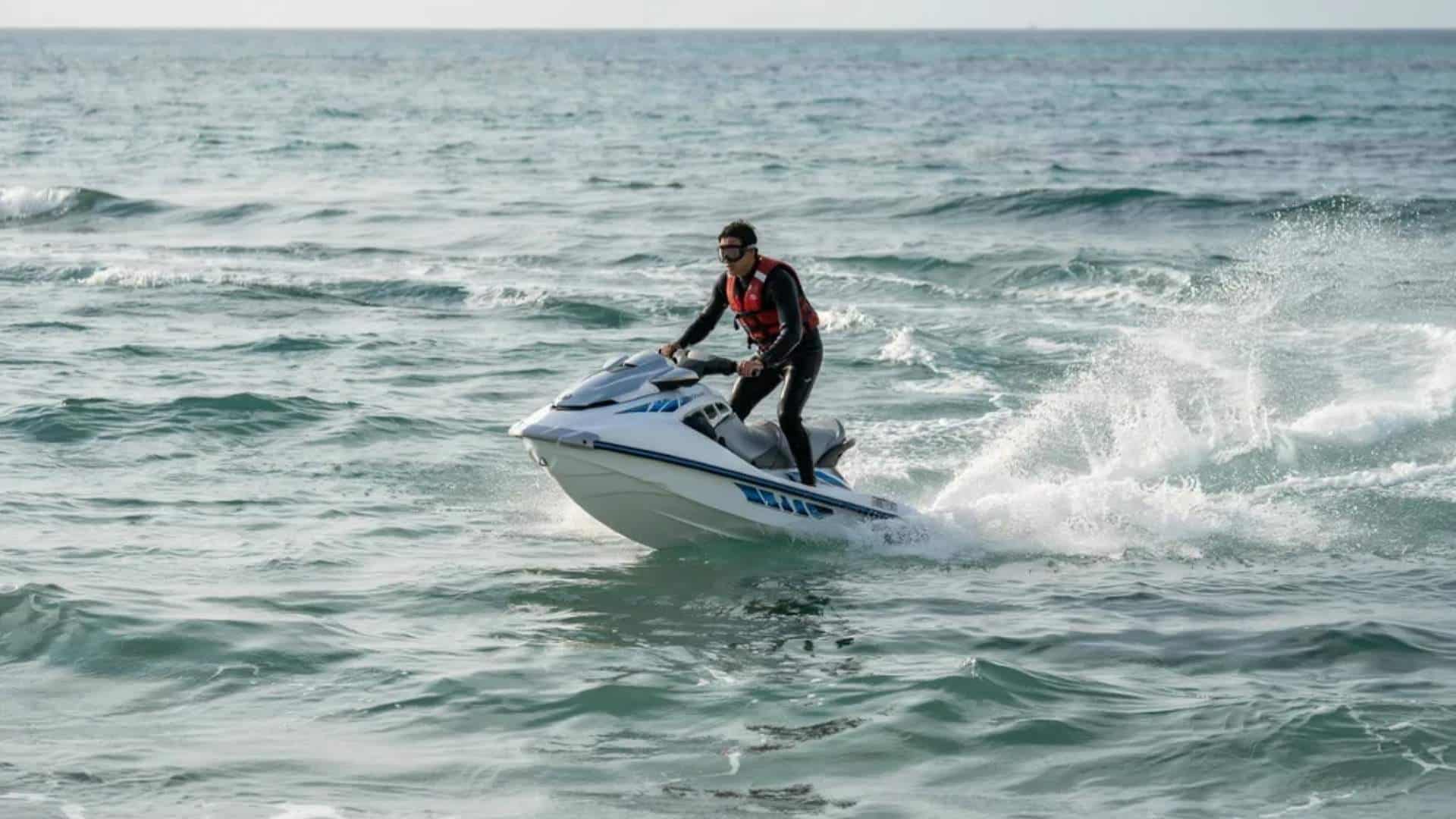 Rider speeding on jet ski across ocean water with spray and motion trail