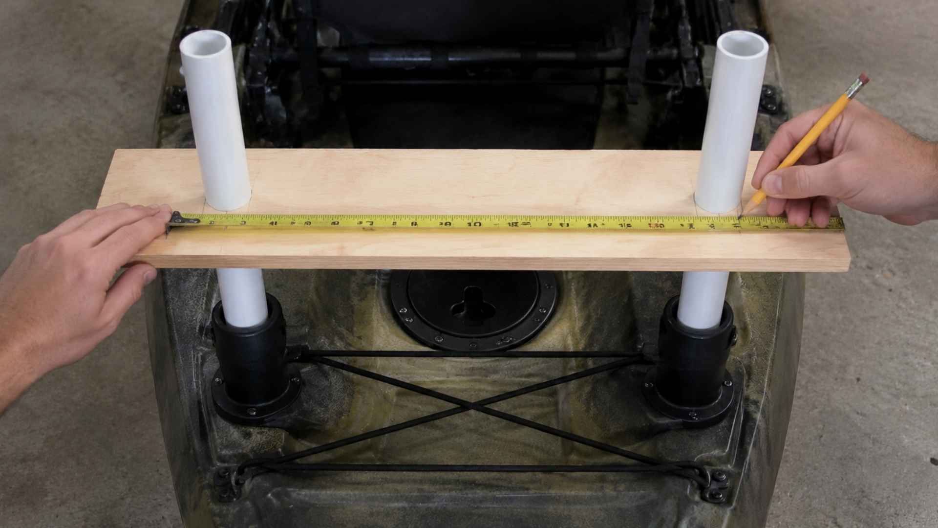 Measuring and marking board across PVC supports on kayak rear deck