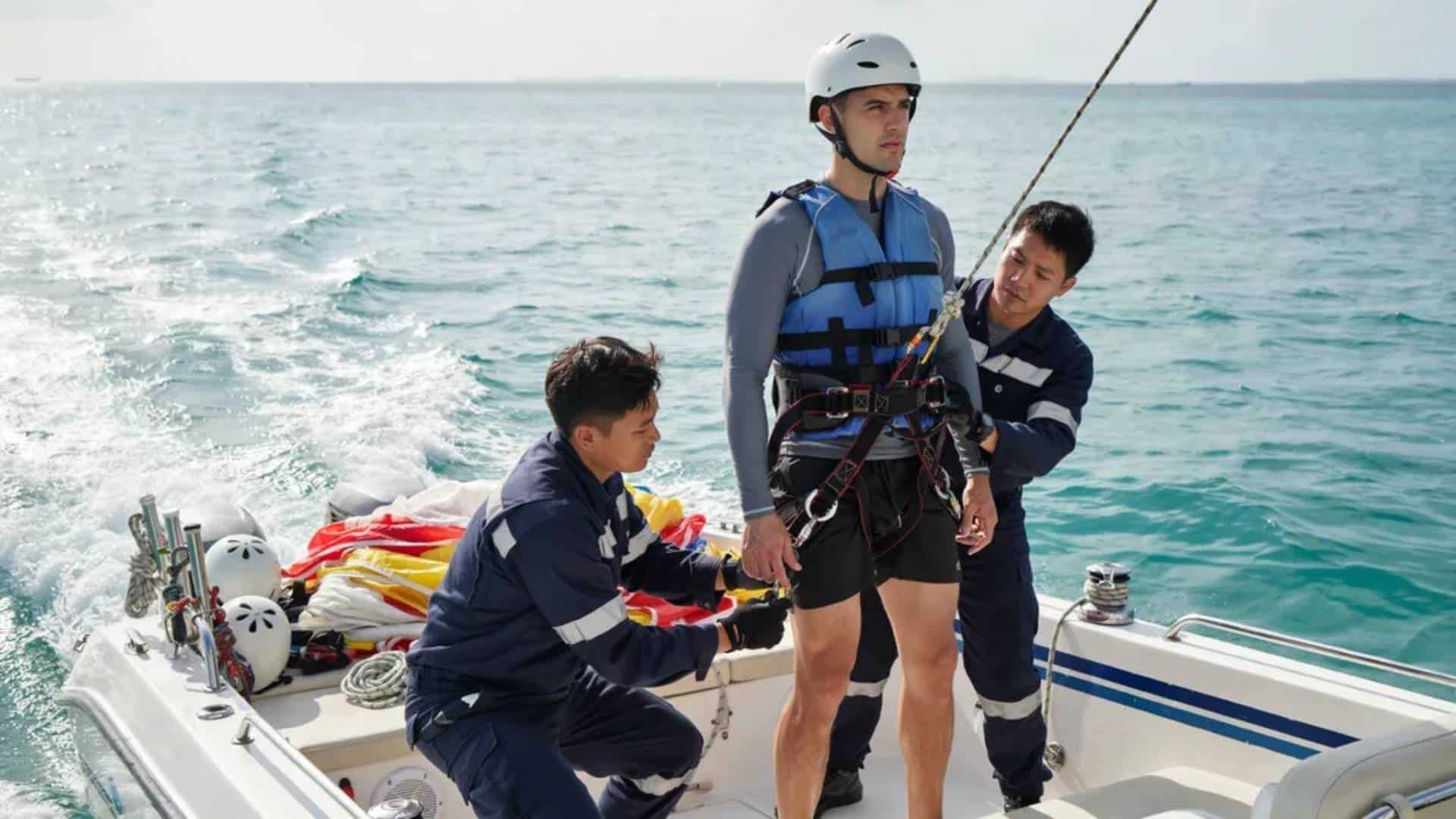 Crew fitting harness on parasailing boat with canopy prepared on tropical water