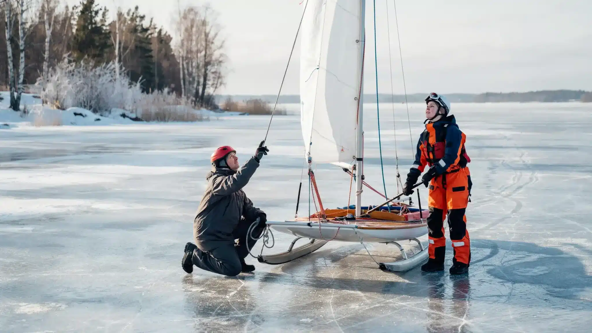 Beginners learning ice sailing while setting up an iceboat on a frozen lake