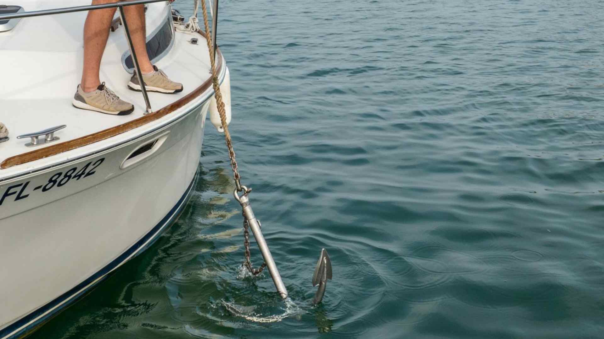 Recreational boat anchored in calm open water with anchor line visible running from the bow