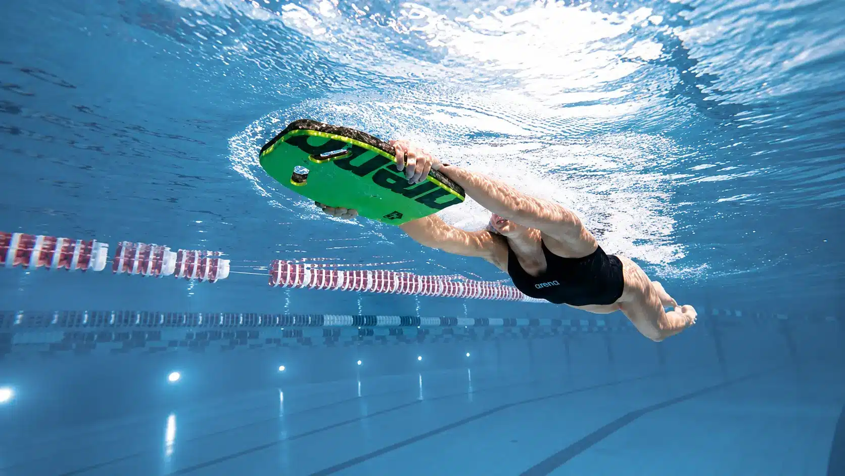 Beginner swimmer practicing a kickboard foundation workout underwater with arms extended and steady body position