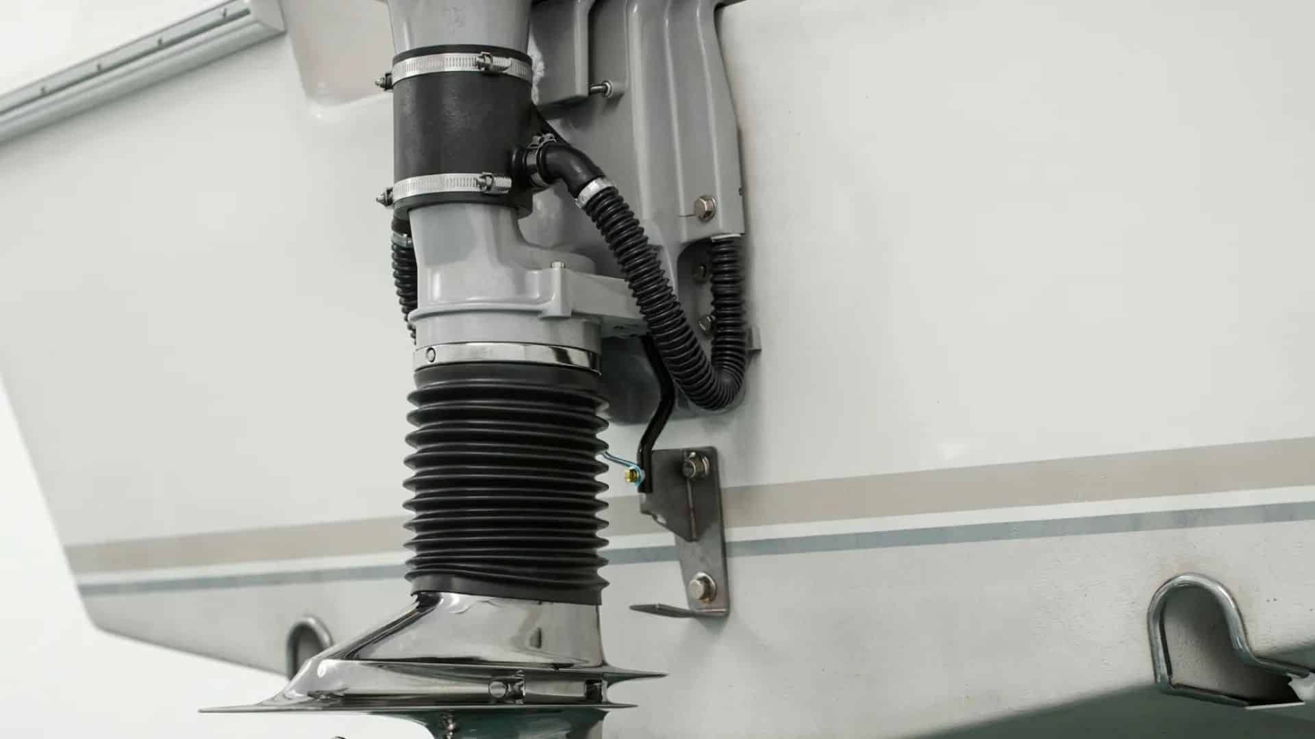 Boat stern showing a black flexible bellows assembly attached near the outdrive area with clamps and mounting hardware