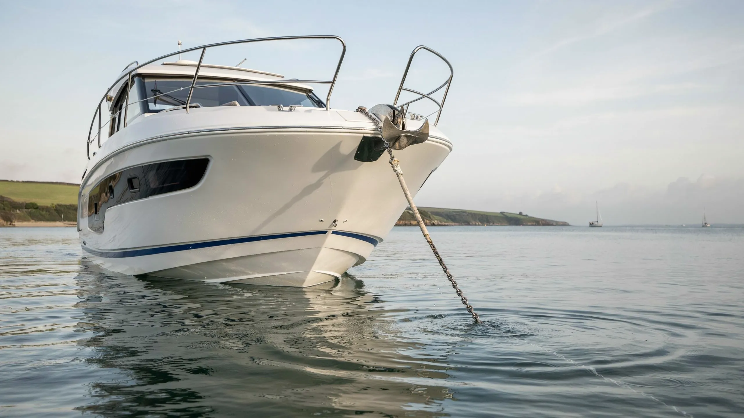 Boater lowering an anchor over the bow into calm water while anchoring a small boat