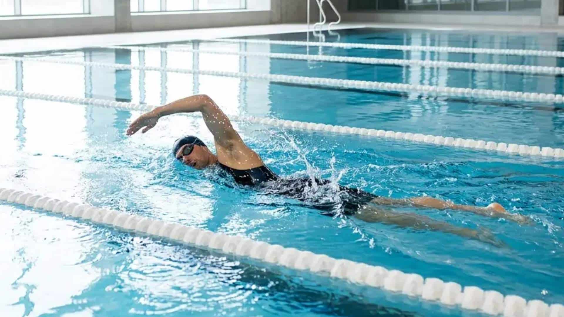 Man swimming freestyle in an indoor lap swimming pool.