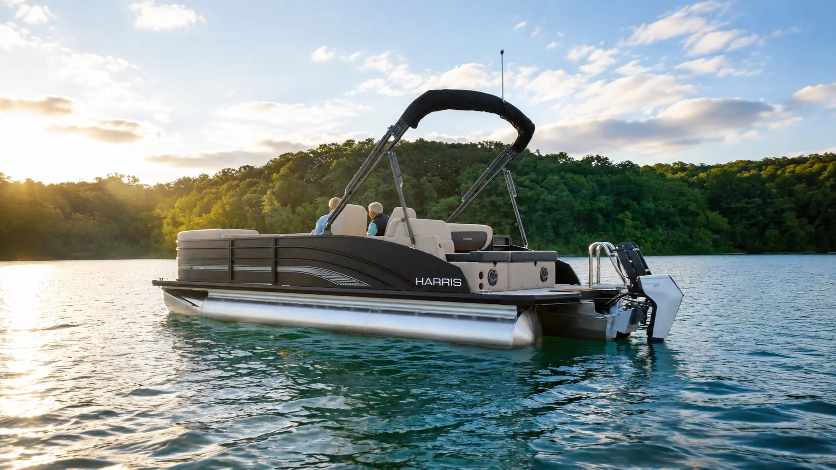 Harris pontoon boat cruising across a lake with passengers onboard
