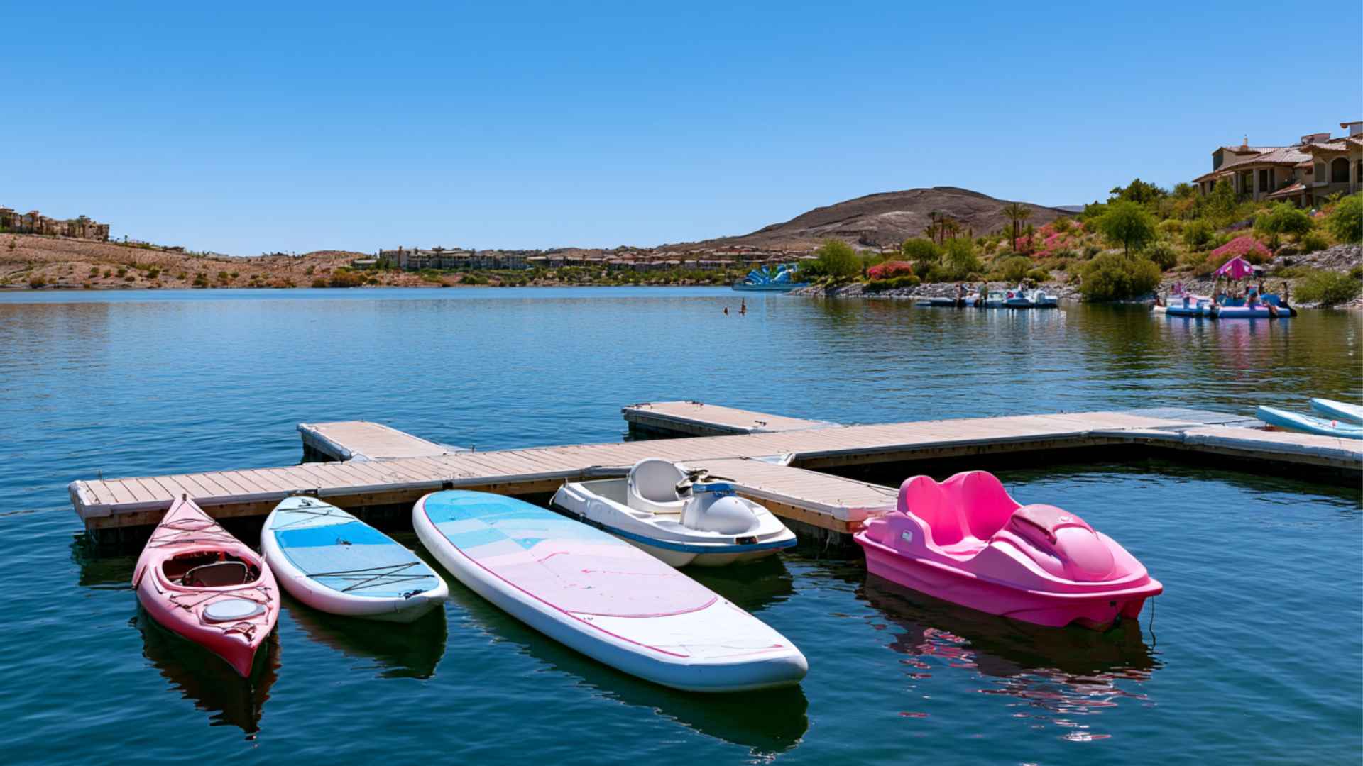Lake Las Vegas Water Sports dock with kayaks, paddleboards, electric boats, and a pink boat on calm blue water