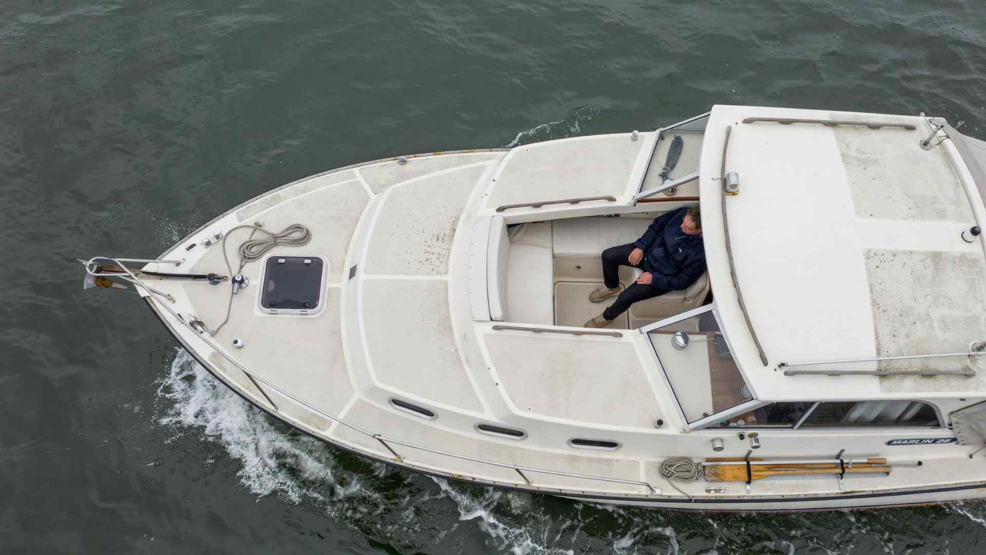 Overhead view of a boat showing a passenger seated near the center of the deck, away from the bow and stern