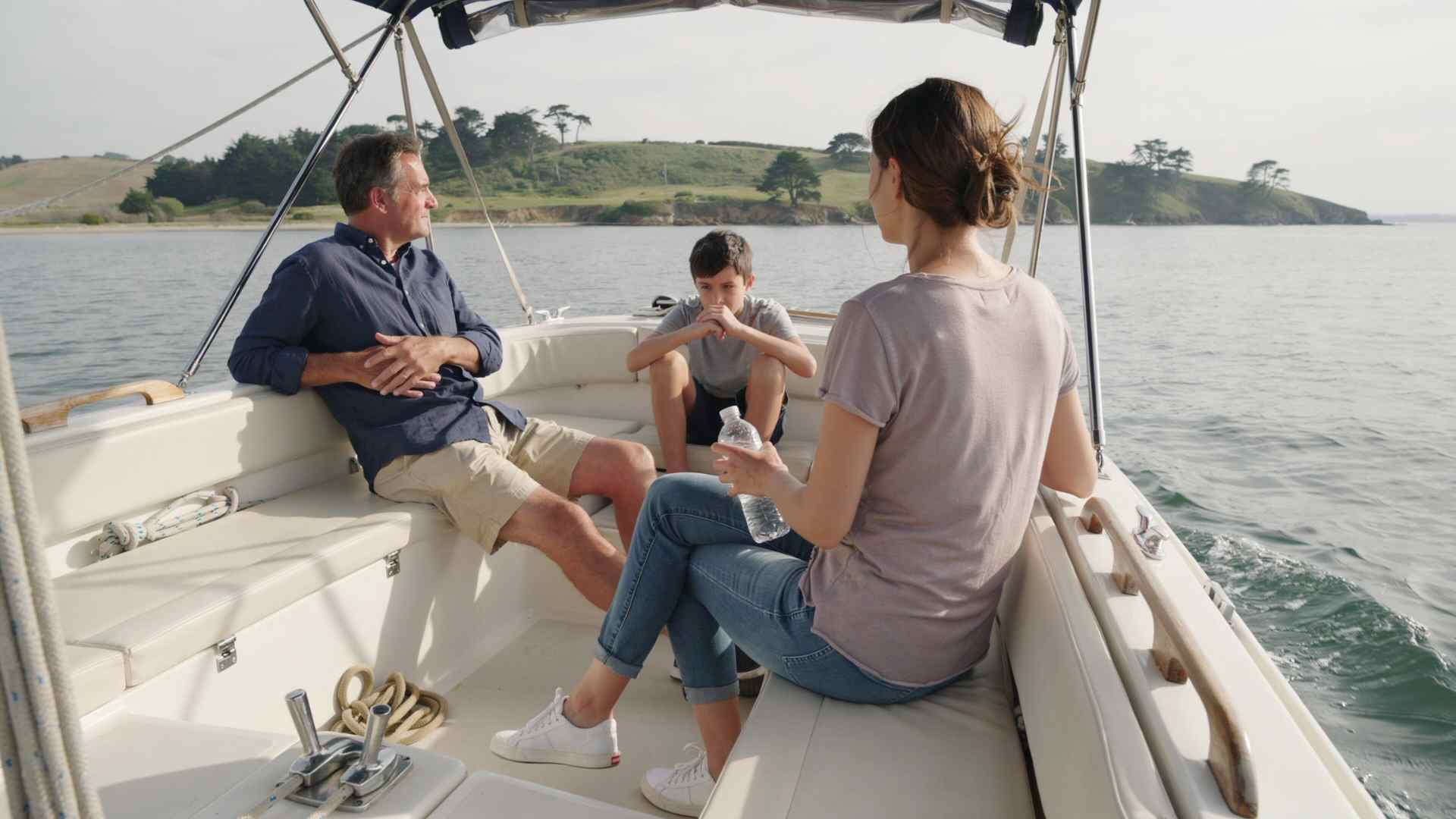 Passenger sits near the center of a boat, looking at the horizon and sipping water to help prevent seasickness