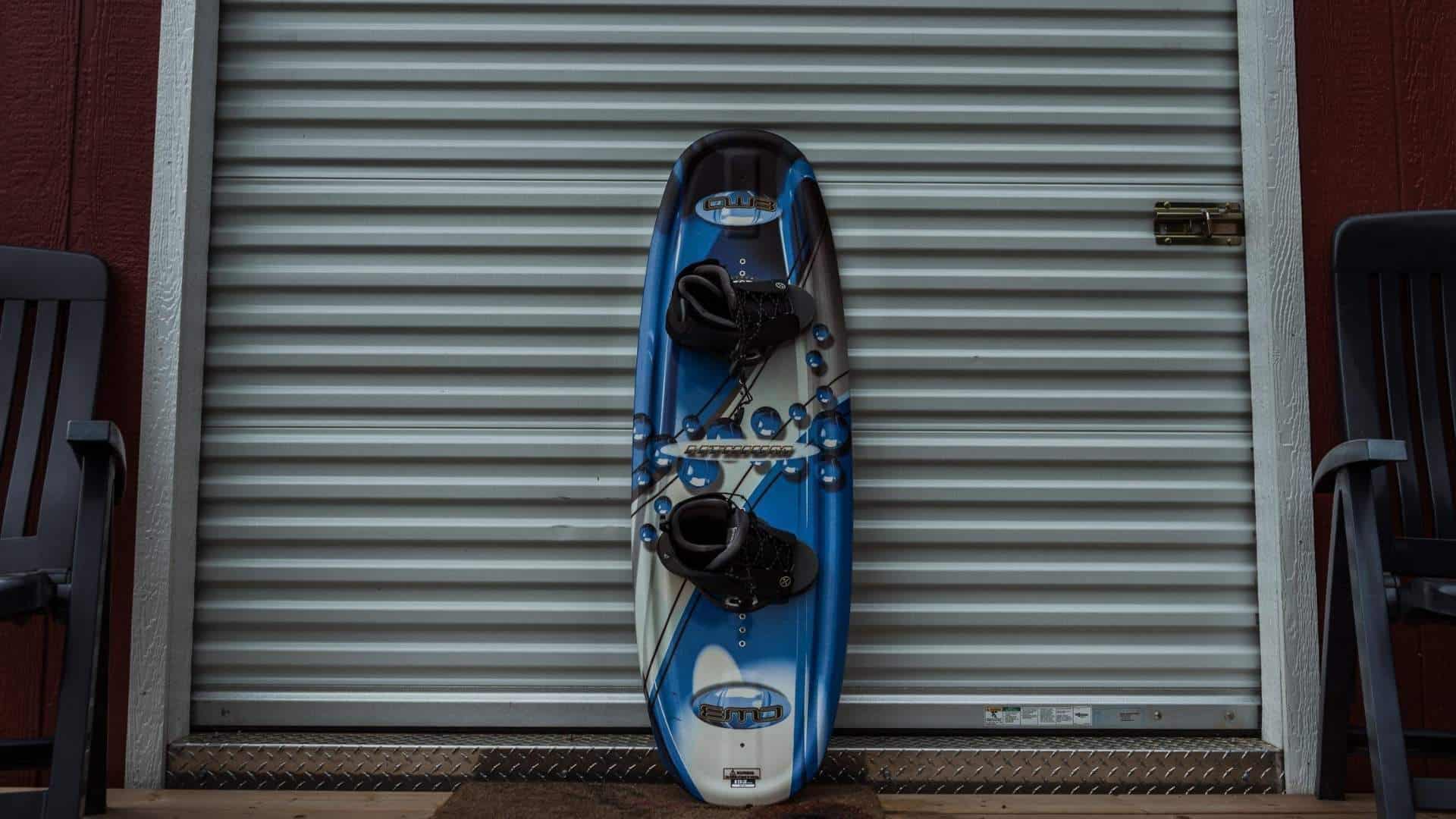 Small wakeboard with bindings displayed upright against a storage door