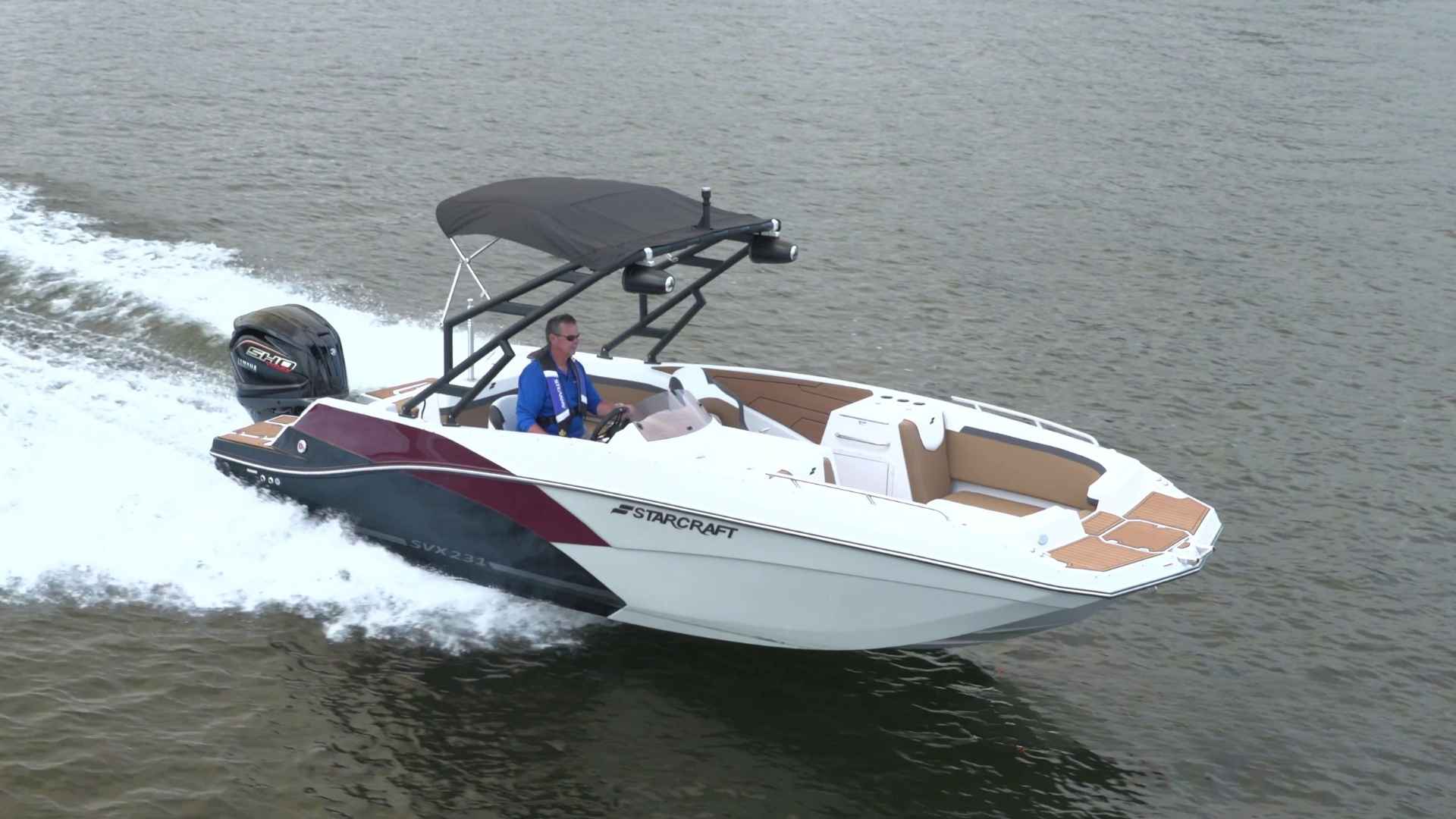 Starcraft SVX 231 OB white deck boat with red accents creating waves while cruising on a large water surface