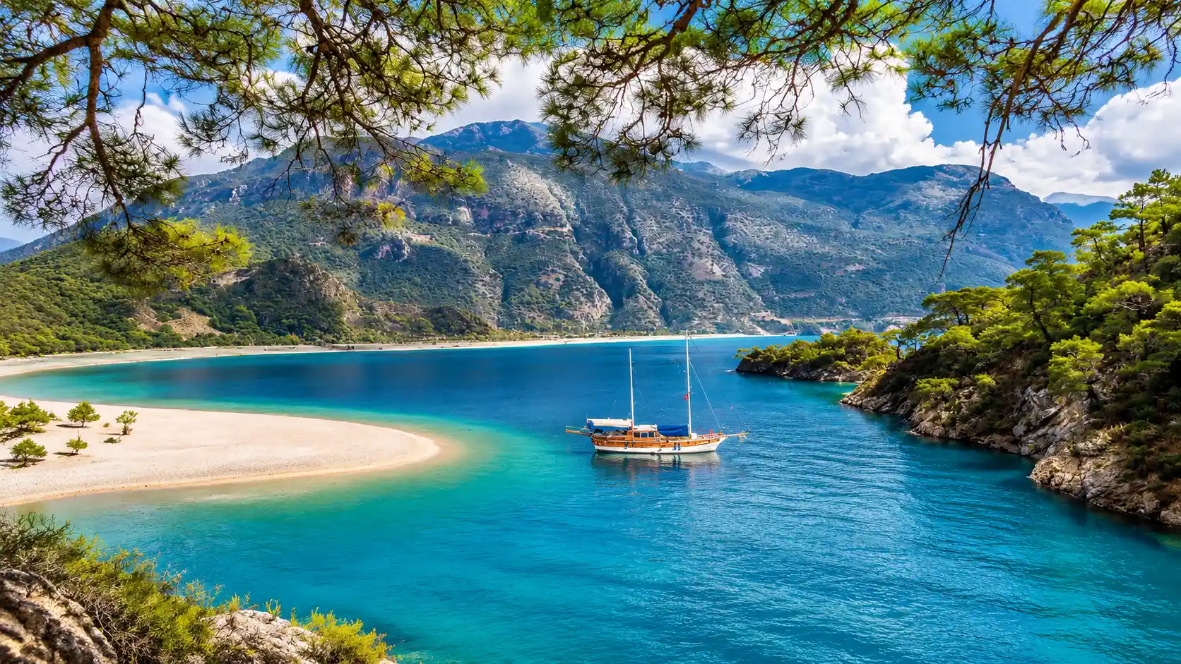 Turquoise Coast with sailboat, pine trees, sandy beach, and rocky cliffs creating a peaceful coastal scene