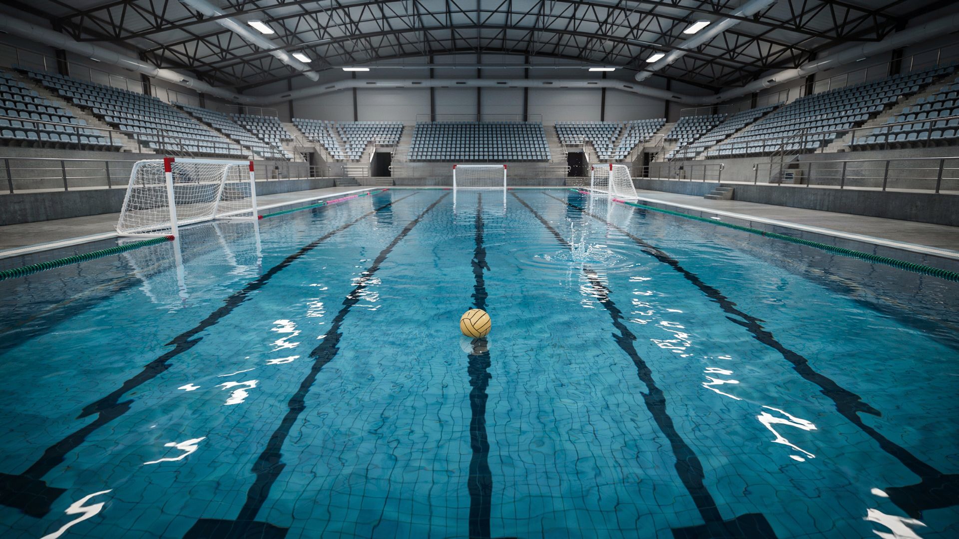 Empty indoor water polo pool with goals, floating ball, and marked playing area showing a professional aquatic sports setup
