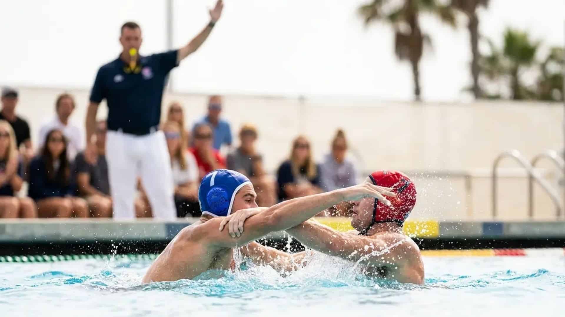 Water polo players in physical contact during a major foul as a referee signals an exclusion call