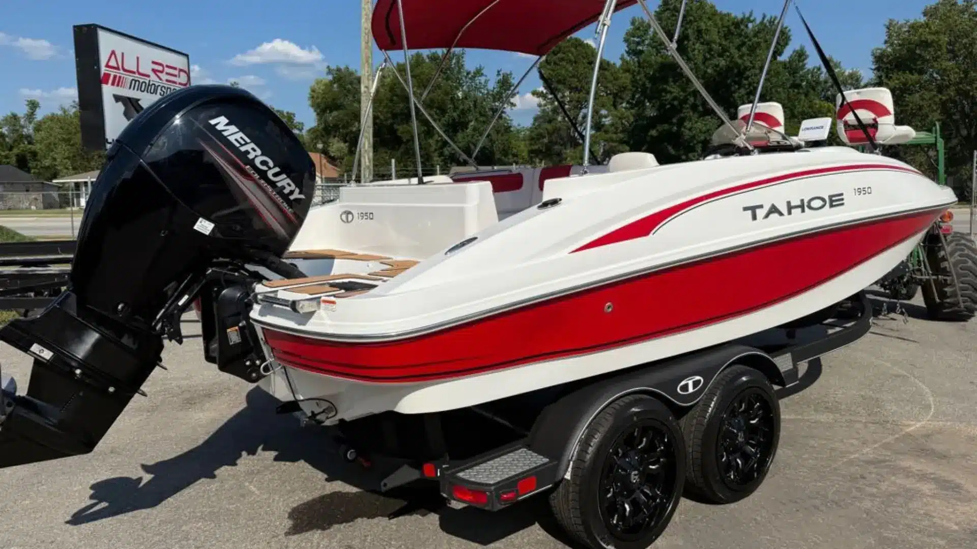 White and red deck boat on trailer showing sleek hull design and outboard motor at dealership