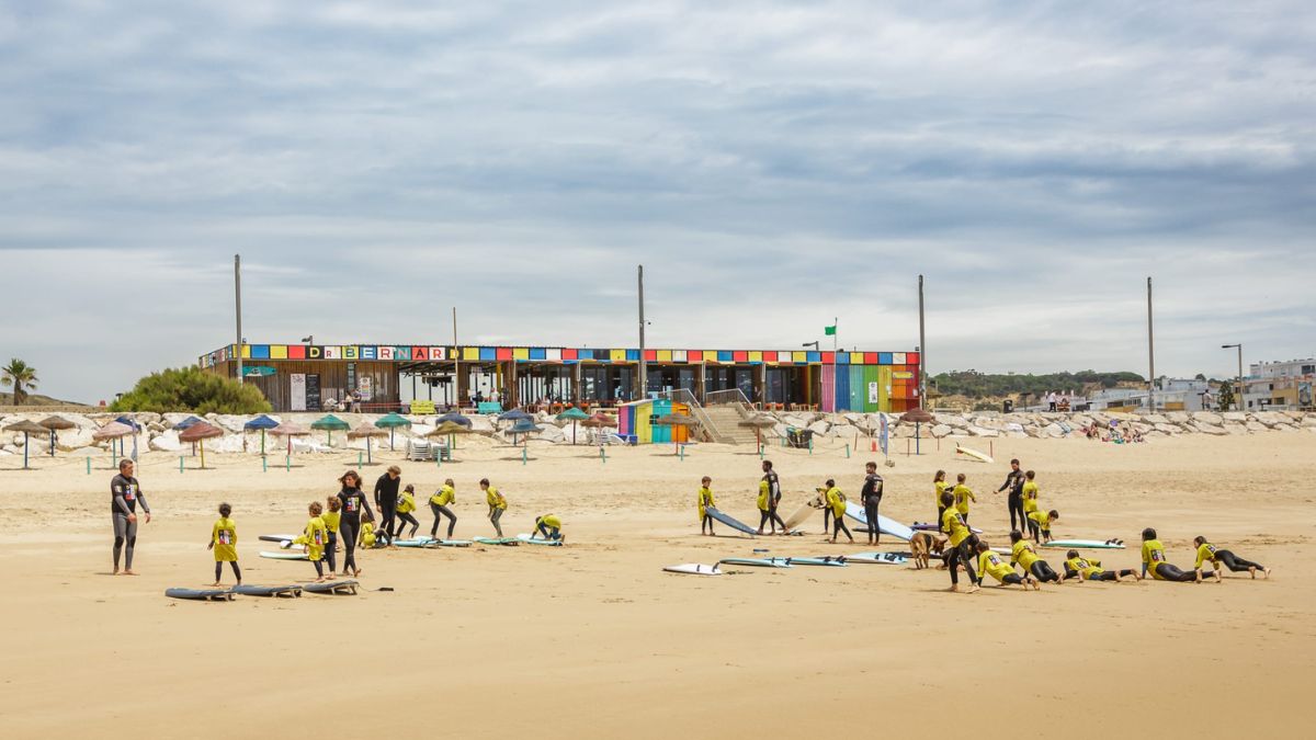 Costa da Caparica beach near Lisbon with surf lessons, boards, and beginners practicing on the sand