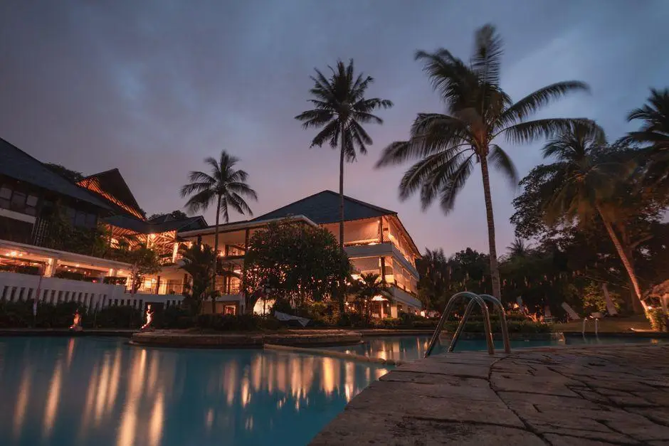 Luxury resort with illuminated poolside and palm trees at dusk